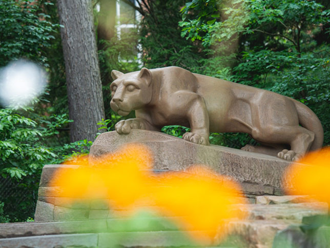 Lion shrine with yellow flowers in foreground.